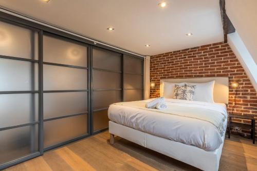 une chambre avec un lit et un mur de briques dans l'établissement Two bedroom apartment in the heart of Old Lille, à Lille