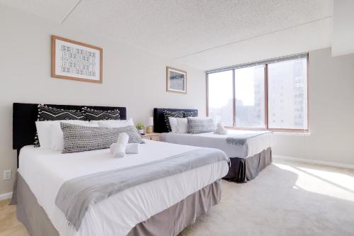 two beds in a white room with a window at Spacious and Minimalist Apartment on Pentagon City in Arlington