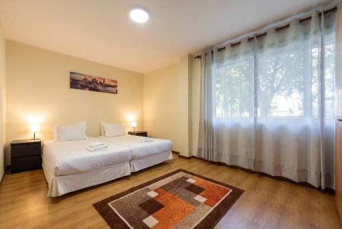 a bedroom with a bed and a large window at Maia's Cozy Apartment in Águas Santas