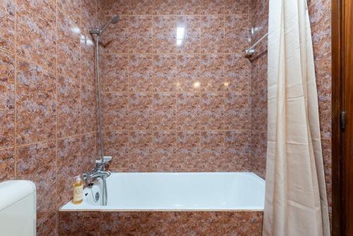 a shower with a white bath tub in a bathroom at Maia's Cozy Apartment in Águas Santas