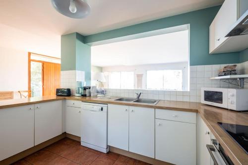 a kitchen with white cabinets and a large window at Villa Tramontane vue panoramique PYLA SUR MER in La Teste-de-Buch
