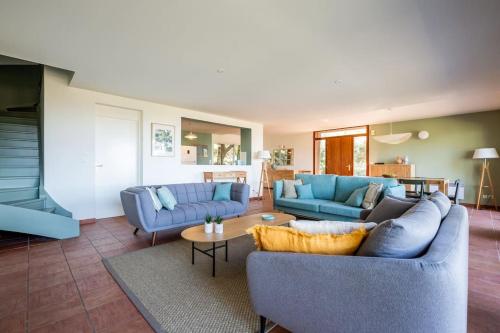 a living room with two blue couches and a table at Villa Tramontane vue panoramique PYLA SUR MER in La Teste-de-Buch