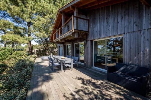 a deck with a table and chairs on a house at Villa Tramontane vue panoramique PYLA SUR MER in La Teste-de-Buch