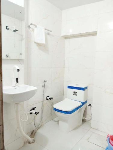 a white bathroom with a toilet and a sink at Walkinn Homestay Near TAJ MAHAL in Tājganj