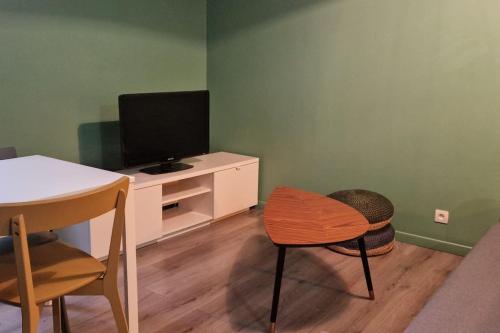 a living room with a tv and a table and a chair at Charmant appartement au calme, proche centre in Aire-sur-lʼAdour