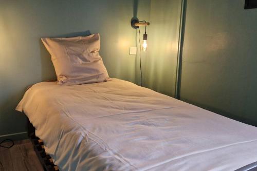 a bed with white sheets and a pillow on it at Charmant appartement au calme, proche centre in Aire-sur-lʼAdour