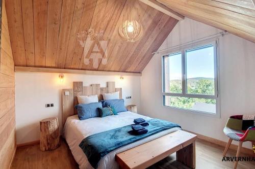 Un dormitorio con una cama grande con techo de madera. en Lona Spa, en Chambon-sur-Lac