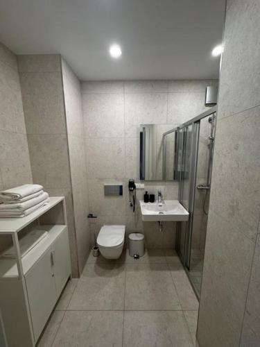 a bathroom with a toilet and a sink and a shower at Albatros Resort SPA in Ķesterciems