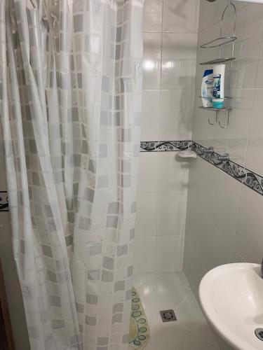 a bathroom with a white shower curtain and a sink at Calazania in Limoncito