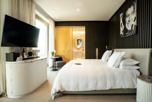 a hotel room with a white bed and a television at The First Musica - Preferred Hotels & Resorts in Rome
