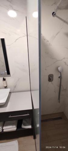 a shower in a bathroom with a white marble wall at HOTEL LOBBY in Bihać