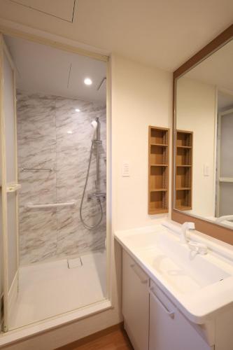 a bathroom with a shower and a sink at Kojohama Onsen Hotel in Shiraoi