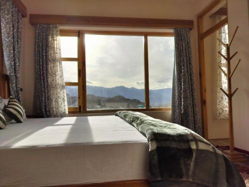 a bedroom with a bed and a large window at Gawa Residency in Leh