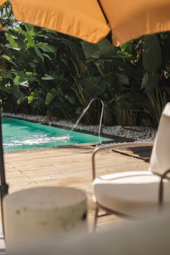a table with an umbrella next to a swimming pool at Casa Cuatro Boutique Hotel - Adults Recommended in Novo Sancti Petri