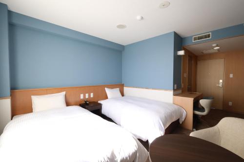 two beds in a room with blue walls at Kojohama Onsen Hotel in Shiraoi