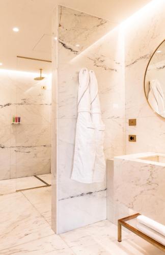 a bathroom with a white marble wall at The First Musica - Preferred Hotels & Resorts in Rome