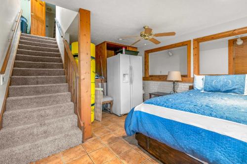 a bedroom with a bed and a staircase with a refrigerator at Walk to Lake Lampe Cabin with Fireplace and Deck! in Lampe