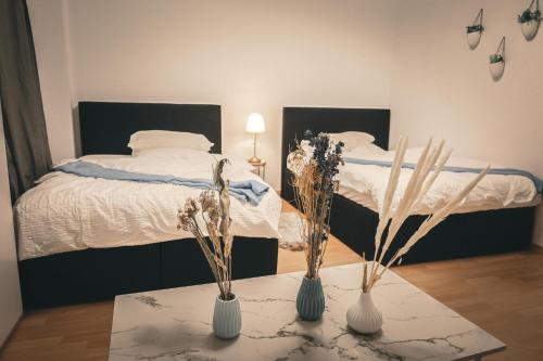 een slaapkamer met twee bedden en een tafel met bloemen bij Bibo City Apartment in Bielefeld