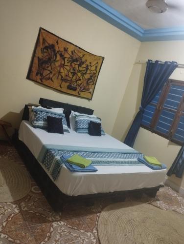 a bedroom with a bed with a painting on the wall at Luca&Irina airport comfort in Zanzibar City