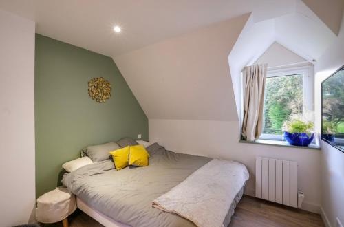 une chambre avec un lit avec des oreillers jaunes et une fenêtre dans l'établissement Maison de charme dans le golf de la baule, à 10 min de la mer, à Saint-André-des-Eaux