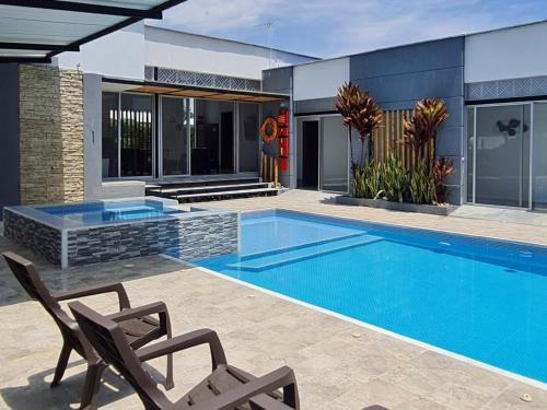 a swimming pool with two chairs next to a house at Villa Tokyo in Ibagué