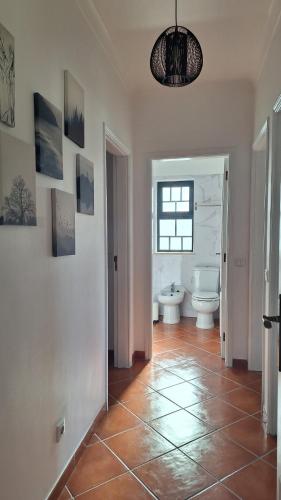 baño con aseo y suelo de baldosa. en Apartamento Olhos do Mar, en Olhos de Água