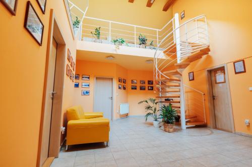 a hallway with a yellow chair and a spiral staircase at Penzion Bene in Chotěboř