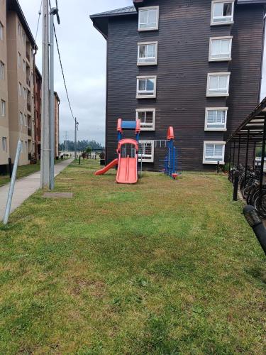 a playground in a yard next to a building at Departamento íntimo y de entorno natural. in Temuco