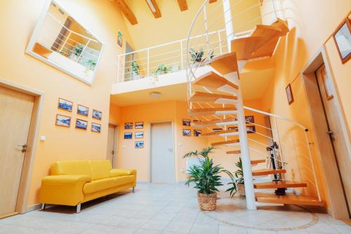 a living room with a yellow couch and a spiral staircase at Penzion Bene in Chotěboř