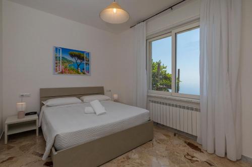 a bedroom with a bed and a large window at Villa Pino in Furore