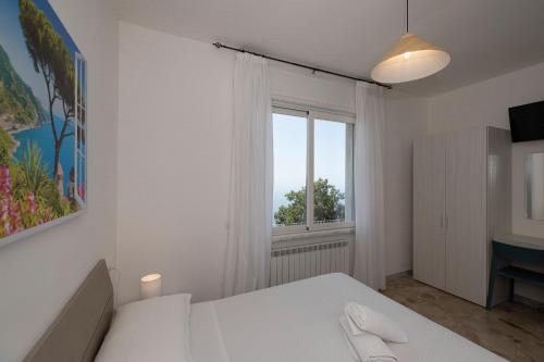 a bedroom with a white bed and a window at Villa Pino in Furore