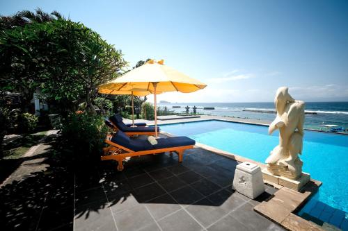 a swimming pool with an umbrella and a chair at Villa Mola Mola in Candidasa