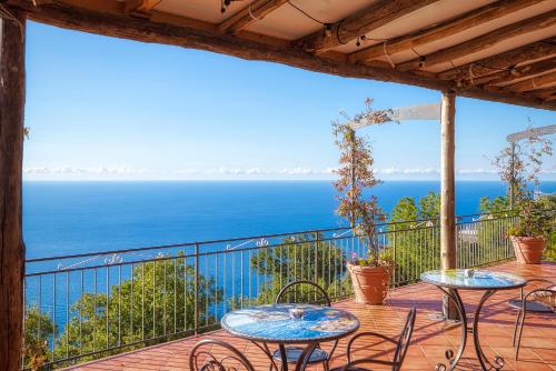a balcony with tables and chairs overlooking the ocean at Villa Pino in Furore