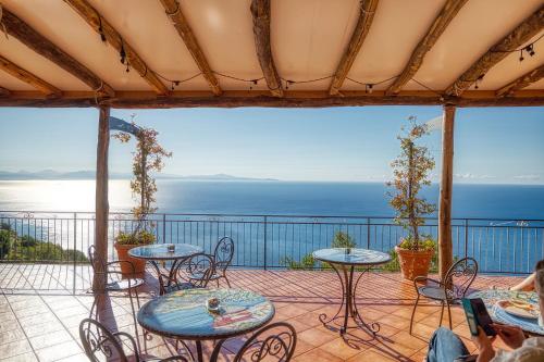 a patio with tables and chairs and a view of the ocean at Villa Pino in Furore