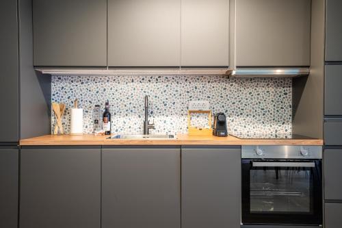 a kitchen counter with a sink and a stove at The Evergreen Apt with Parking & Netflix - Romexpo, Piața Presei, Expoziției, Herăstrău in Bucharest
