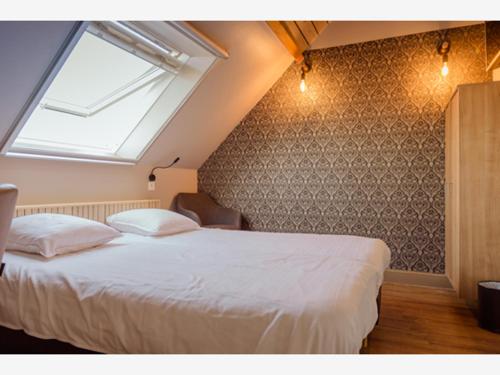 a bedroom with a large white bed with a window at Oud Gemeentehuis in Poelkapelle