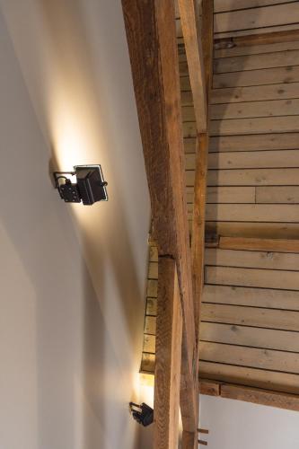 a wooden staircase with a light on the wall at Oud Gemeentehuis in Poelkapelle