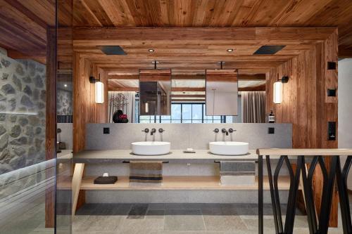 two sinks in a bathroom with wooden walls at BelArosa Chalet - the luxury hideaway in the Swiss Alps in Arosa