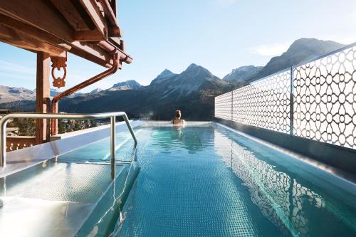 a woman in a swimming pool with mountains in the background at BelArosa Chalet - the luxury hideaway in the Swiss Alps in Arosa