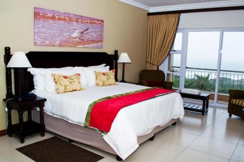 a bedroom with a large bed and a balcony at Umthunzi Hotel and Conference in Umtentweni