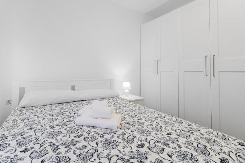 a white bedroom with a large bed with a pillow at Urban Nest Suites in Las Palmas de Gran Canaria