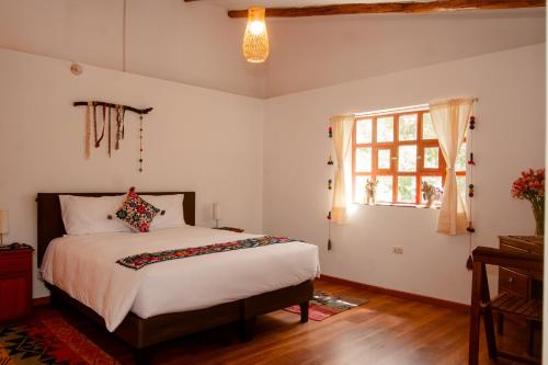a bedroom with a bed and a window at La Rosa Wellness Lodge in Urubamba
