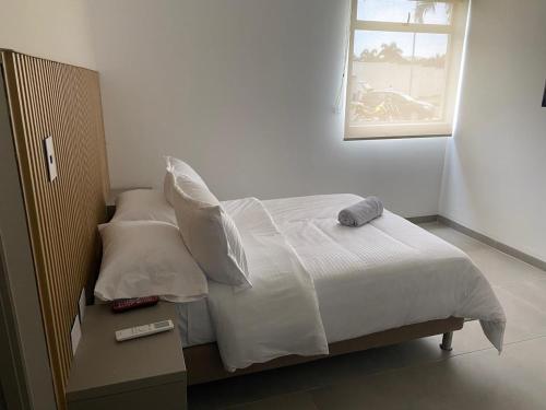a bedroom with a bed with white sheets and a window at Hotel las Olas Yumbo in Yumbo