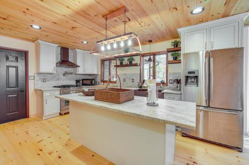 a kitchen with white cabinets and a stainless steel refrigerator at Ski, Hike and More Spacious Log Cabin in Long Pond in Long Pond
