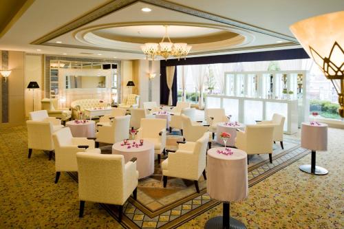 a dining room with white chairs and tables and a chandelier at Koriyama View Hotel in Koriyama