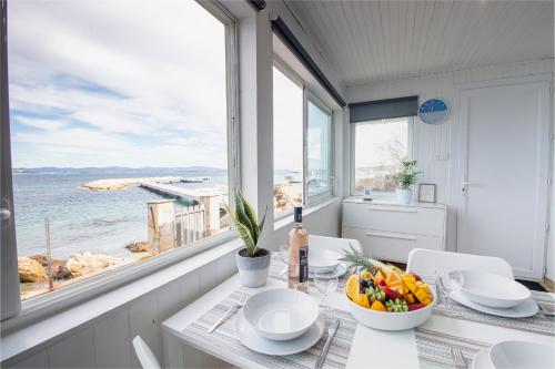 - une salle à manger avec une table et un bol de fruits dans l'établissement La Roche, cabanon cosy les pieds dans l'eau avec vue exceptionnelle, à Hyères