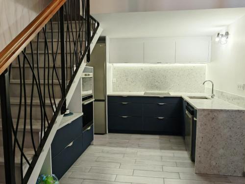 une cuisine avec des armoires bleues et un escalier dans l'établissement Le Mazet Sooksabai, confort, charme et découverte en Petite Camargue, à Saint-Laurent-dʼAigouze