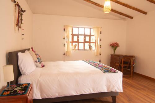 a bedroom with a white bed and a window at La Rosa Wellness Lodge in Urubamba