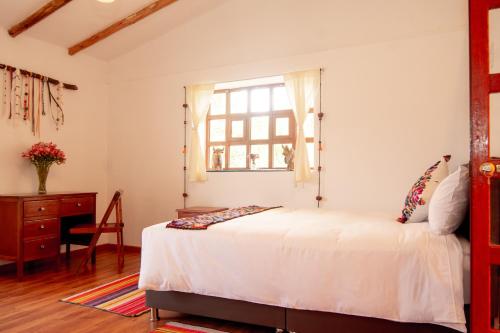a bedroom with a white bed and a window at La Rosa Wellness Lodge in Urubamba