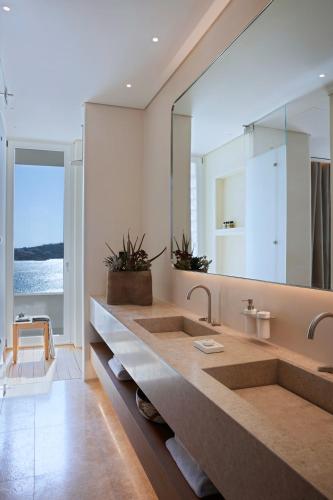 a bathroom with two sinks and a large mirror at The Coast Bill&Coo-The Leading Hotels of the World in Agios Ioannis Mykonos